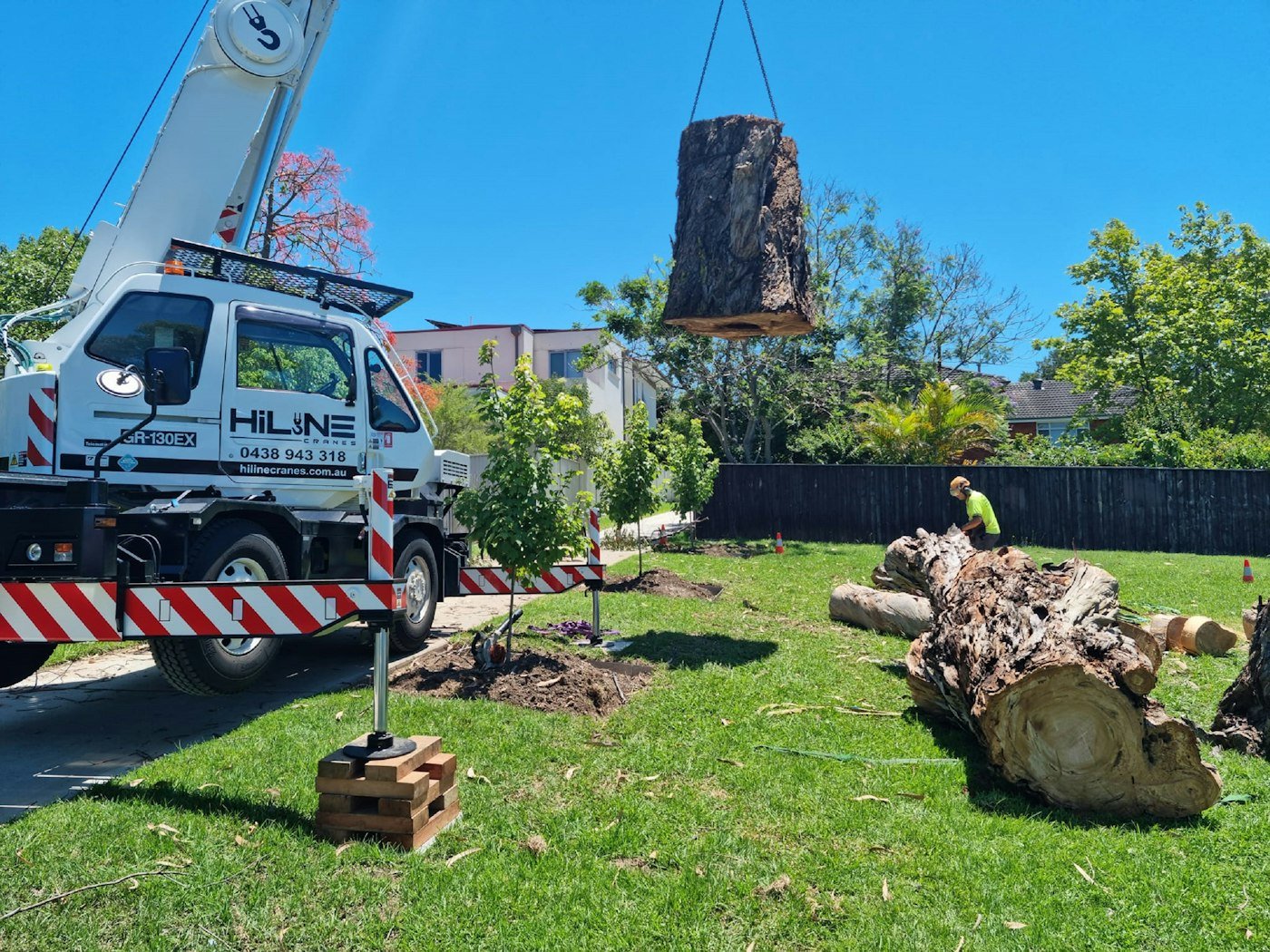 Grue levant une section de tronc au-dessus d’un jardin, méthode employée par notre élagueur à Albi